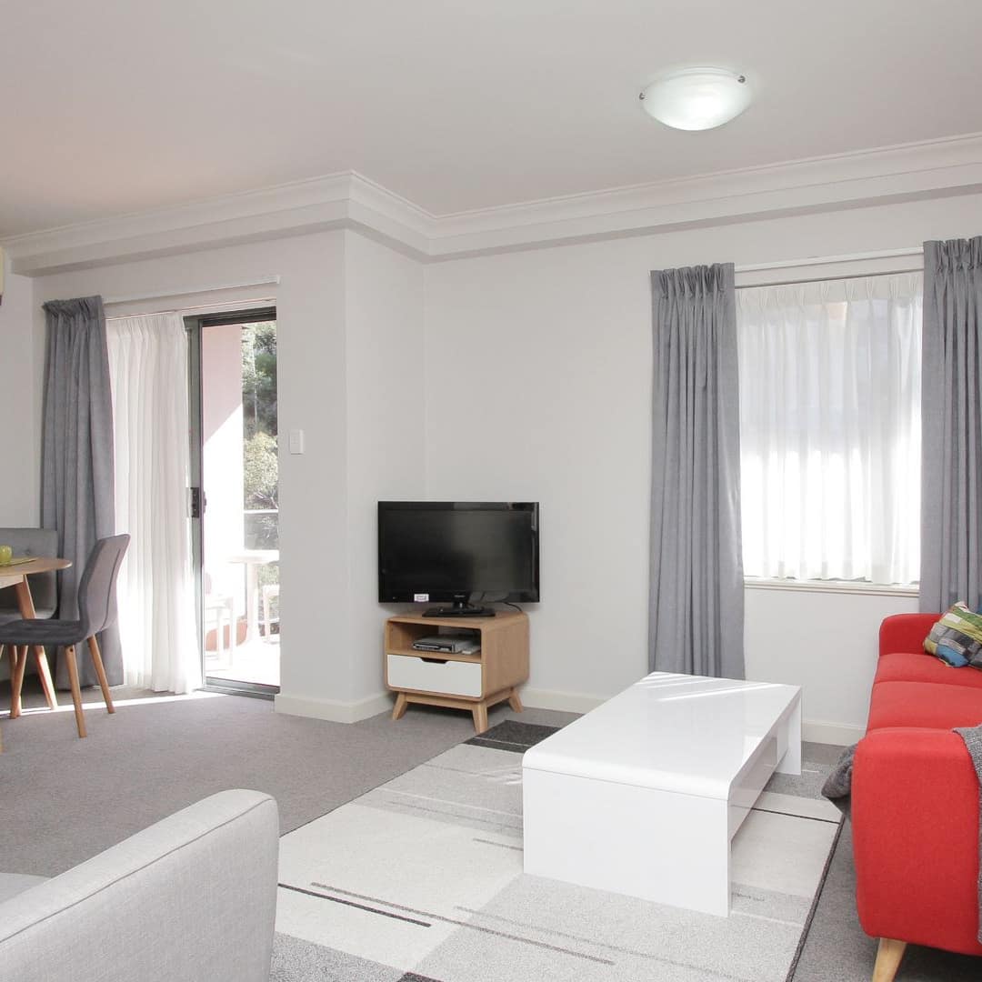 Fun-inspired living room with red sofa, colourful pillows and artwork and small dining table