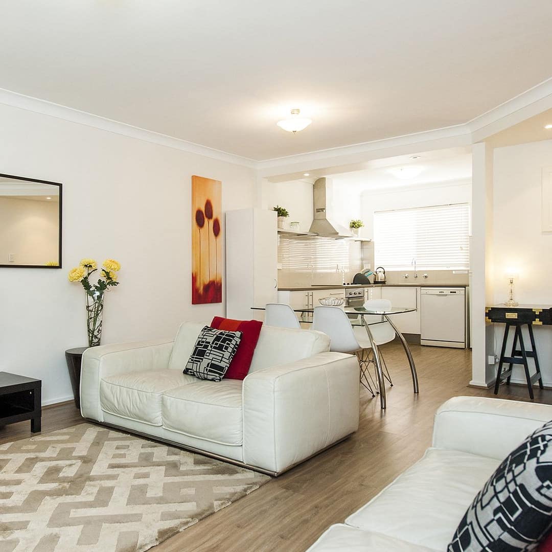 Living room of family-friendly apartment with white sofas, mirror and dining table
