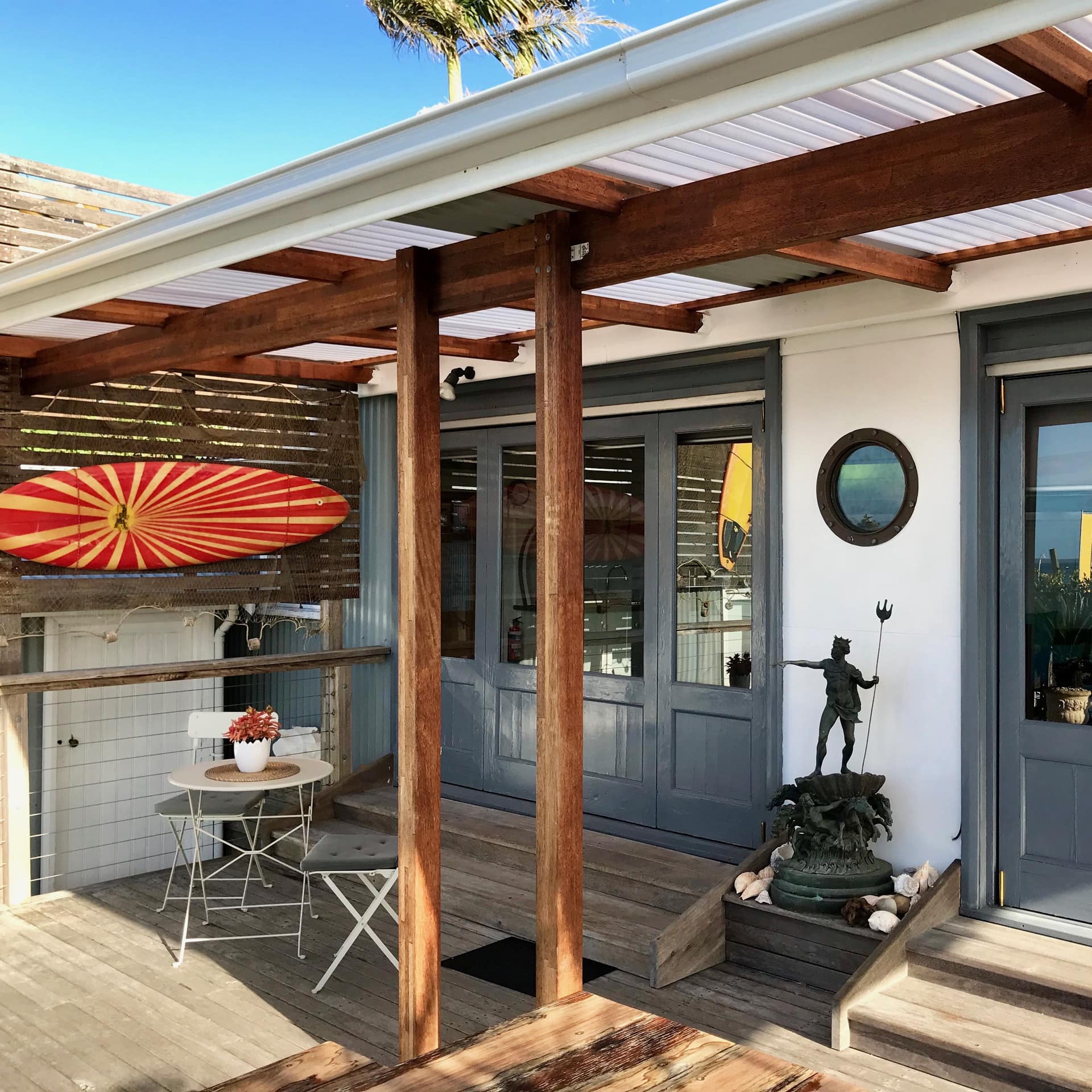 Front entrance of 1-bedroom absolute waterfront cabin with many windows, a covered, wood front deck and a statue of Poseidon