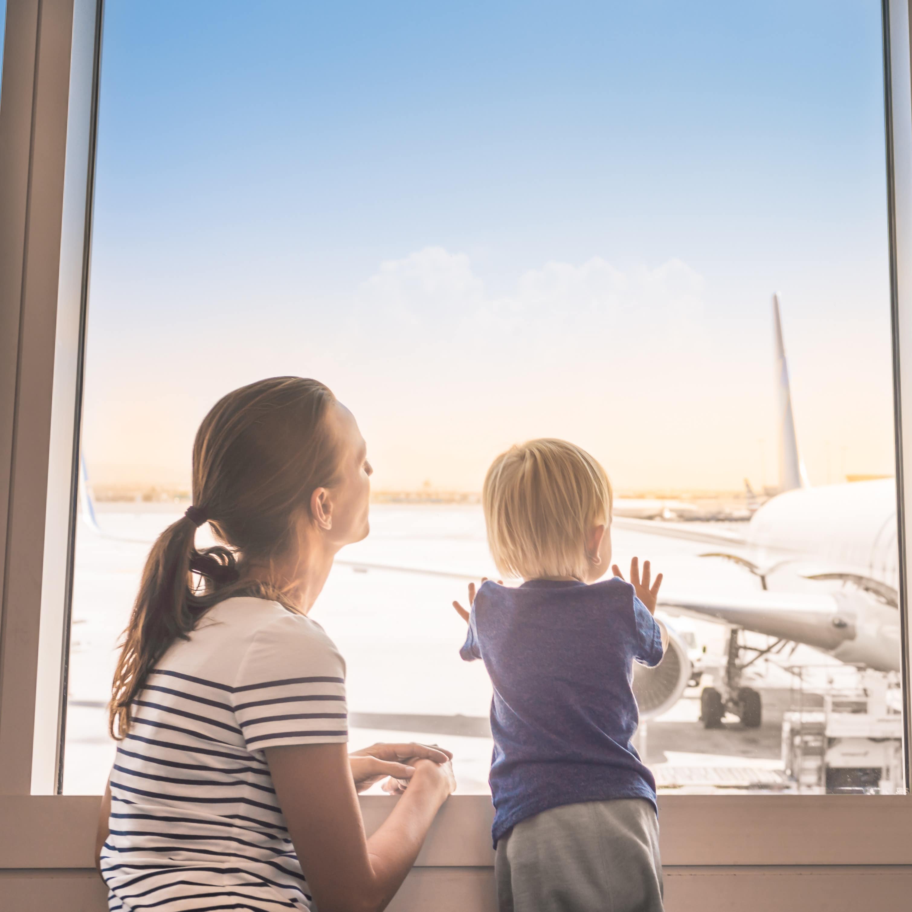 Mother and son looking out window at airplane