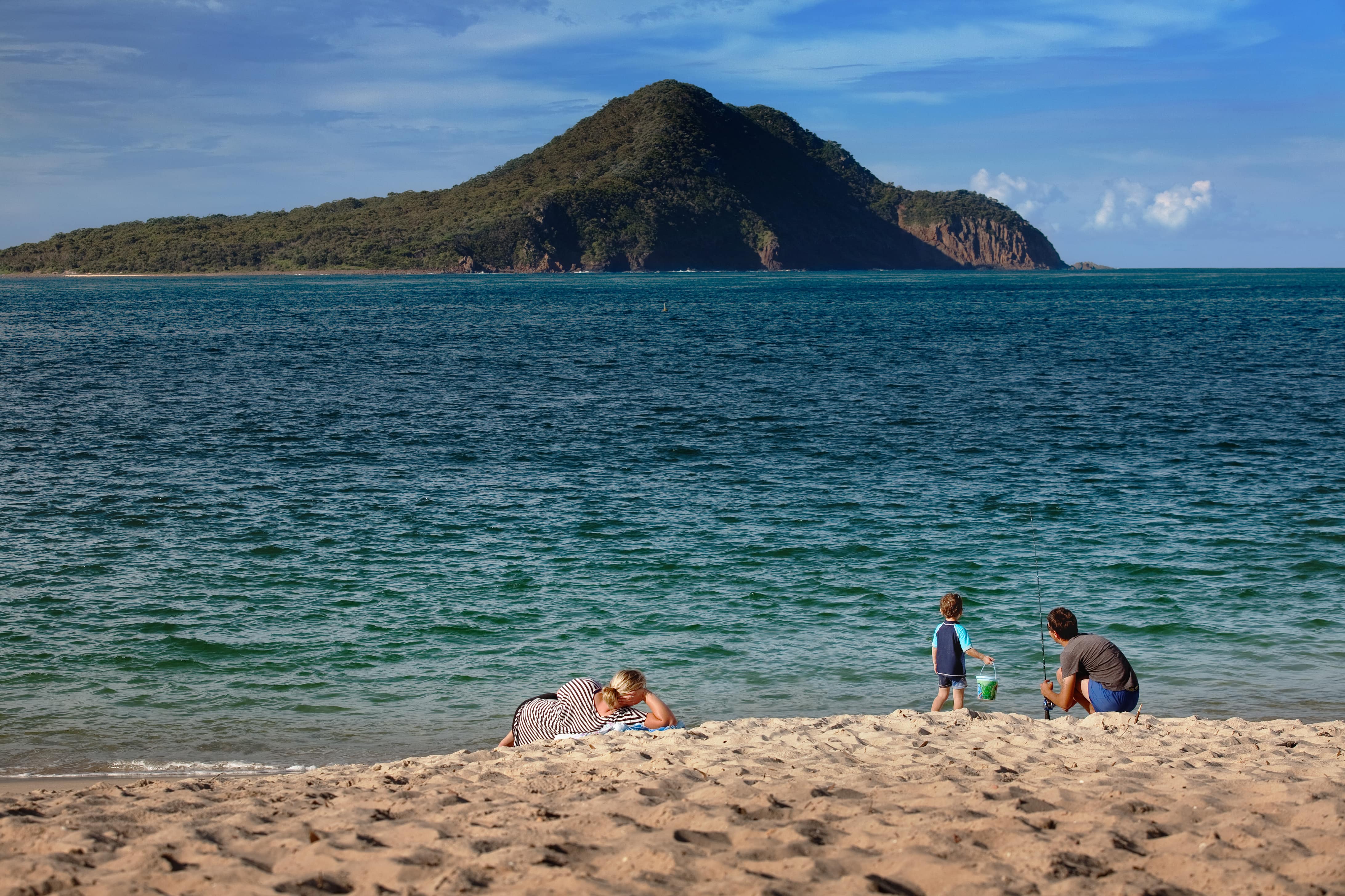 mom, dad and son casting a fishing line from the shore in port nelson