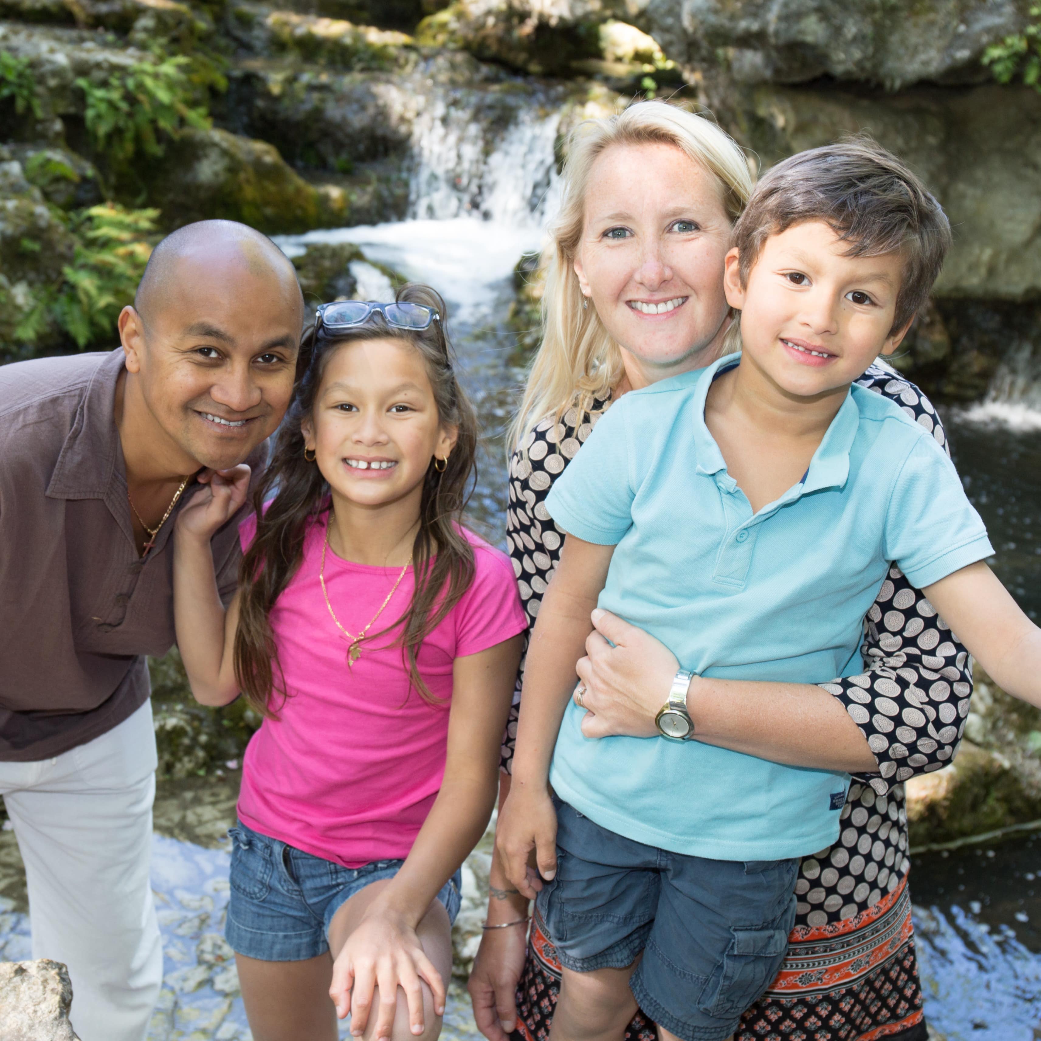 Family of four in front of a waterfall in the mountains